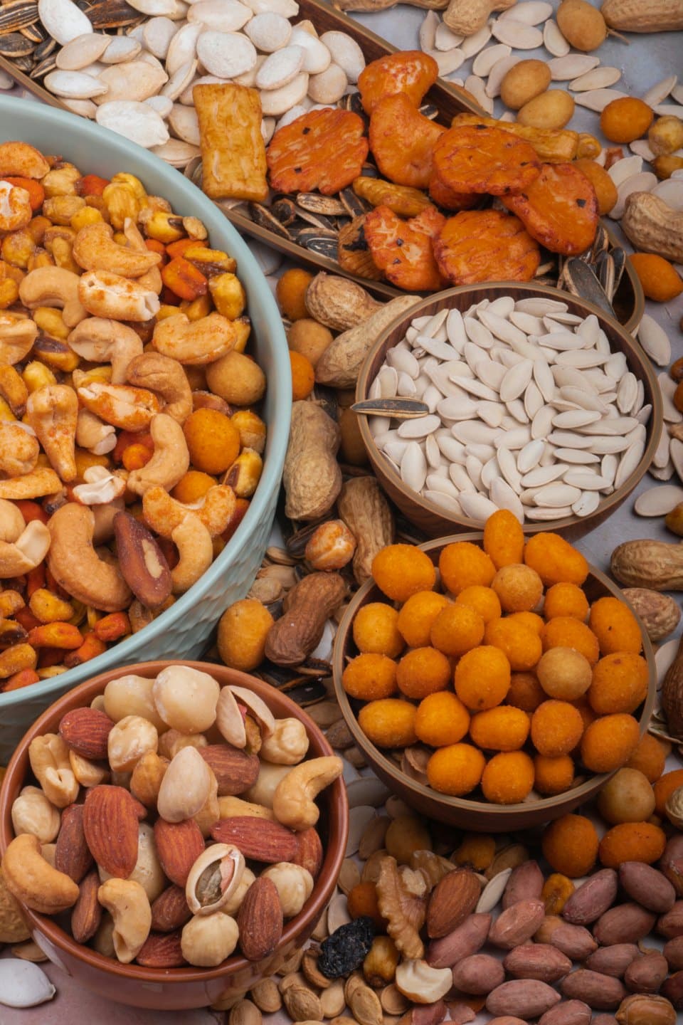 Cuencos de frutos secos y semillas variados dispuestos sobre una superficie.
