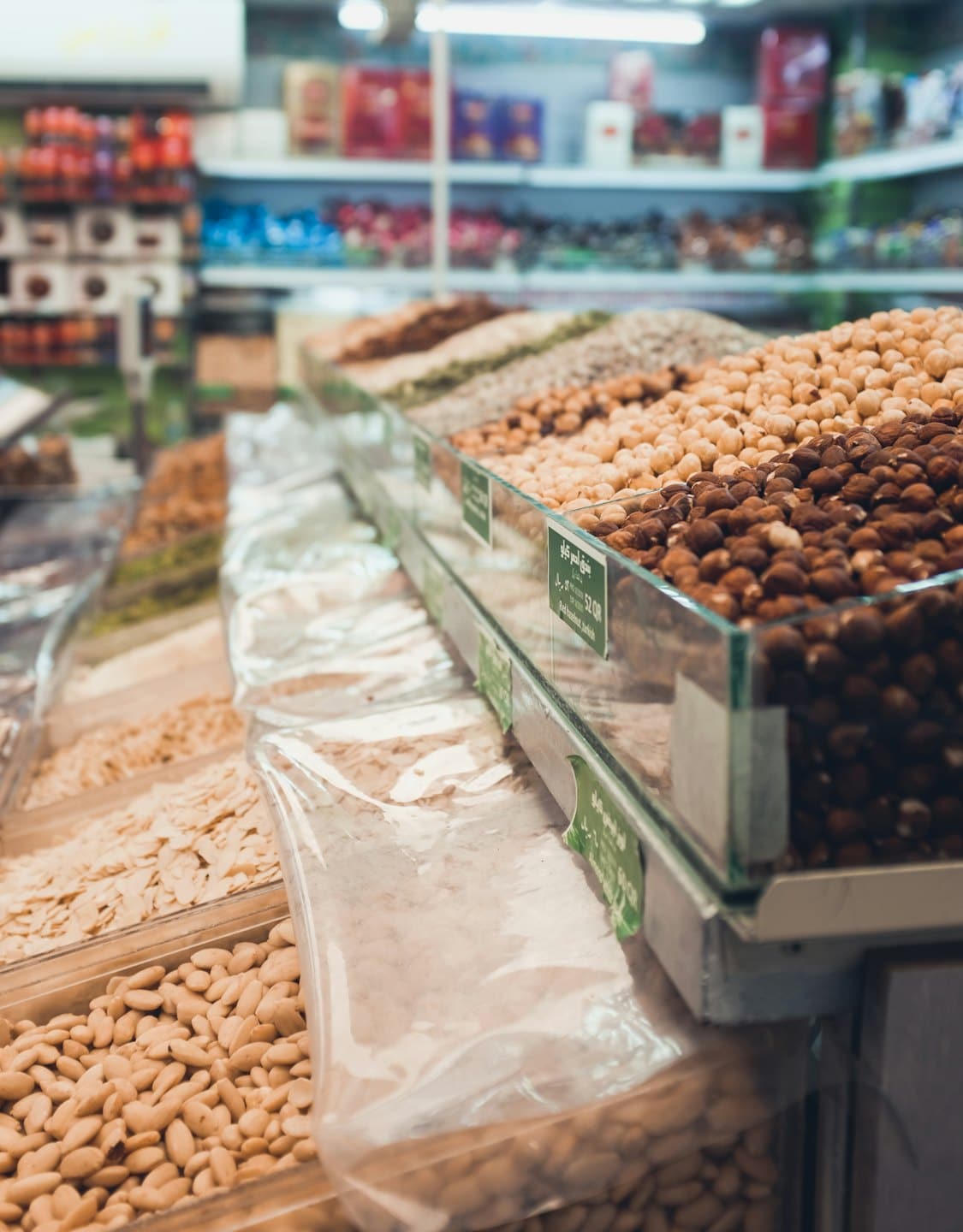 Contenedores a granel llenos de frutos secos y legumbres variados en una tienda.