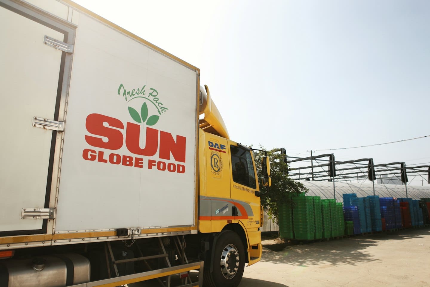 Camión de comida SUN GLOBE FOOD con empaque fresco, estacionado afuera de una instalación de distribución.