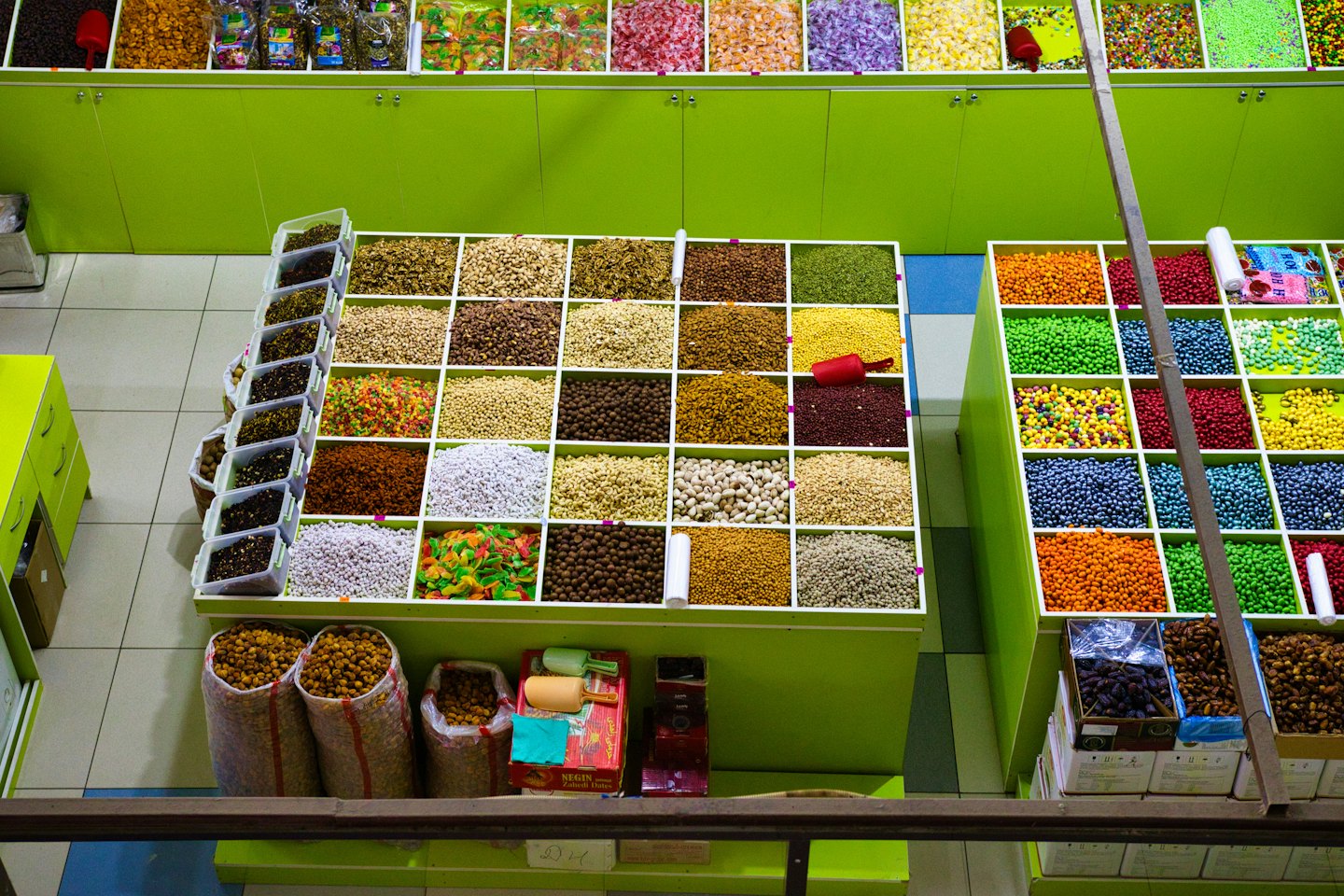 Puesto de mercado a granel con contenedores de frutos secos, semillas y caramelos.