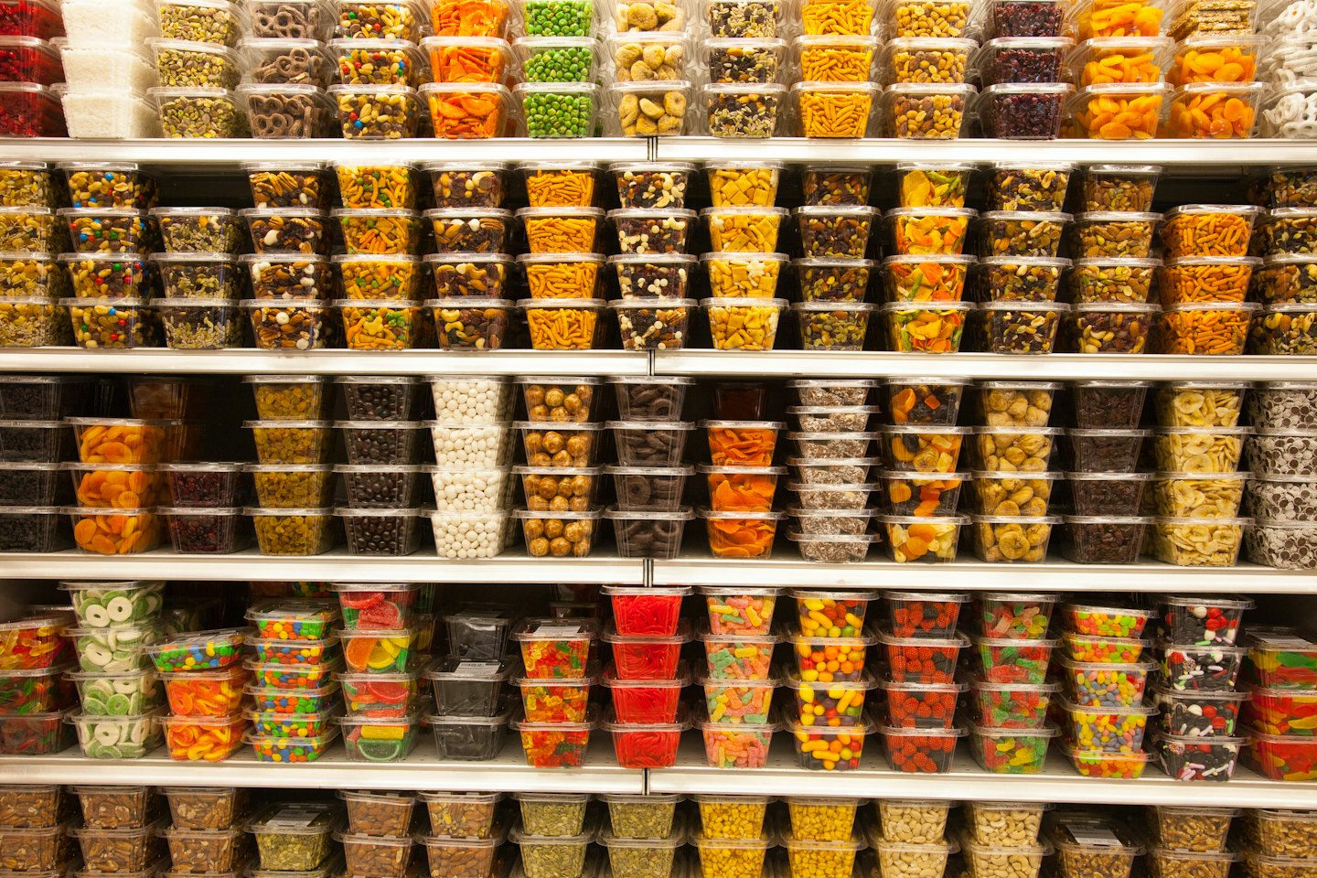 Estantes repletos de recipientes transparentes con surtido de bocadillos y dulces.